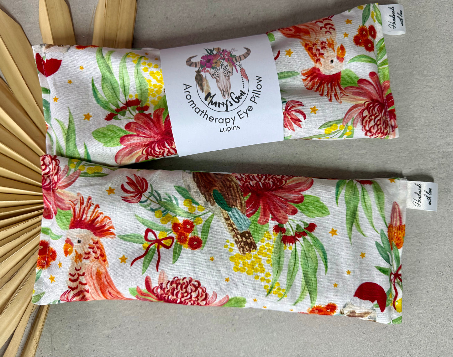 Floral-patterned eye pillows with a label on a gray surface